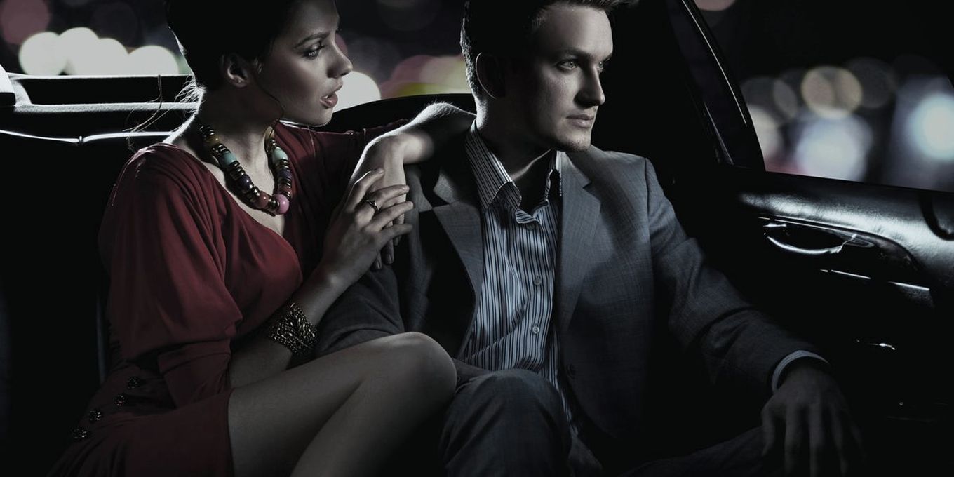Dos pasajeros en el asiento trasero de un coche con conductor, de noche