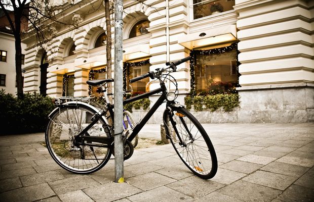 Una bicicleta atada a una farola en la acera de una calle con soportales