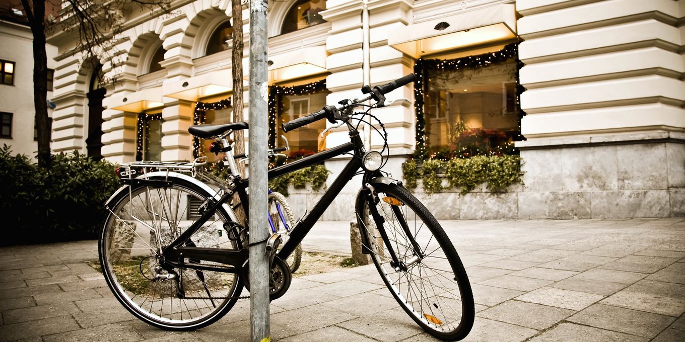 Una bicicleta atada a una farola en la acera de una calle con soportales