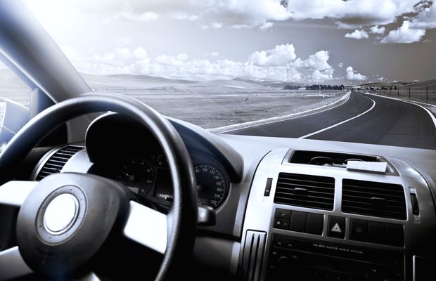 Volante y salpicadero de un coche frente a una carretera que se pierde en la curva
