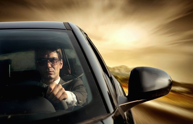 Un conductor al volante de su coche, con la calle desenfocada por la velocidad